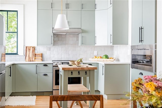 kitchen featuring appliances with stainless steel finishes, light countertops, a healthy amount of sunlight, and extractor fan