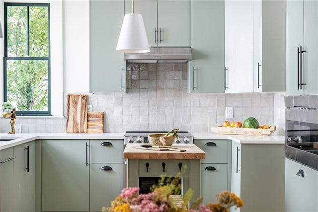 kitchen featuring cooktop, light countertops, backsplash, oven, and under cabinet range hood