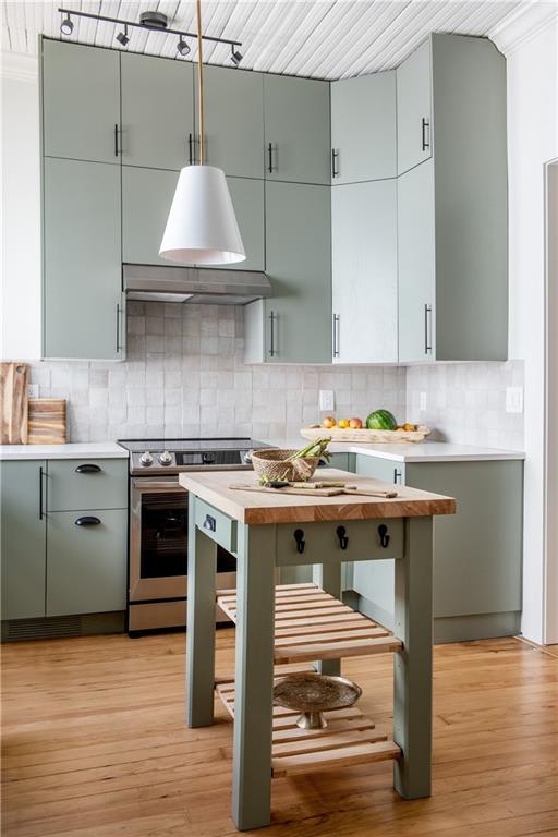 kitchen featuring light wood-type flooring, stainless steel electric stove, light countertops, and backsplash