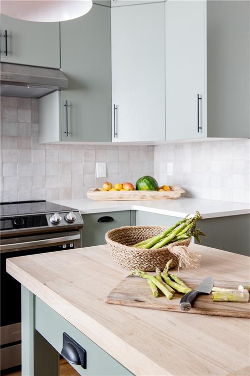 kitchen with light countertops, extractor fan, backsplash, and stainless steel electric stove