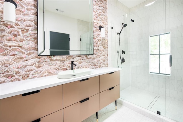 bathroom with tiled shower, vanity, and visible vents