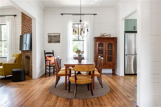 dining room featuring a chandelier, hardwood / wood-style floors, and a brick fireplace