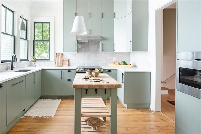 kitchen featuring light wood finished floors, light countertops, tasteful backsplash, and stainless steel range with electric cooktop