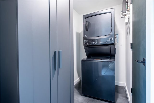 laundry area with laundry area, baseboards, and stacked washer and clothes dryer