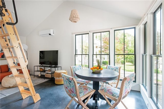 dining room with concrete flooring, high vaulted ceiling, a wall mounted AC, and a healthy amount of sunlight