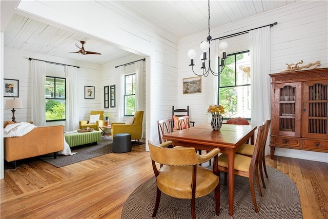 dining area with ceiling fan with notable chandelier, wood-type flooring, wooden ceiling, and a healthy amount of sunlight