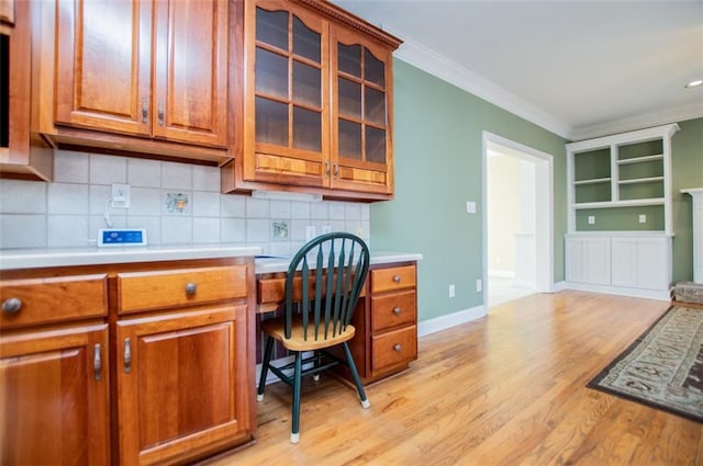 office area with light wood finished floors, ornamental molding, built in study area, and baseboards