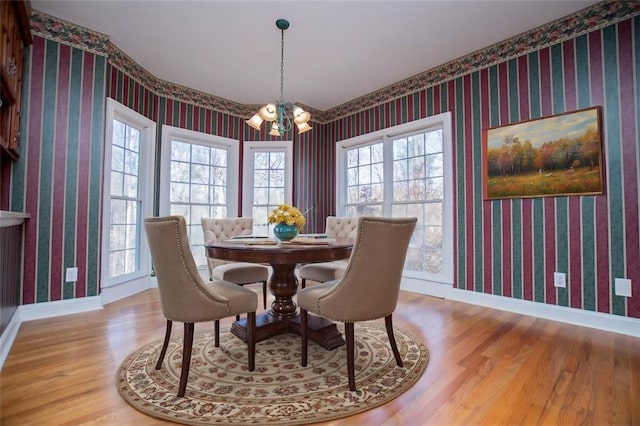 dining space with a chandelier, baseboards, and wallpapered walls