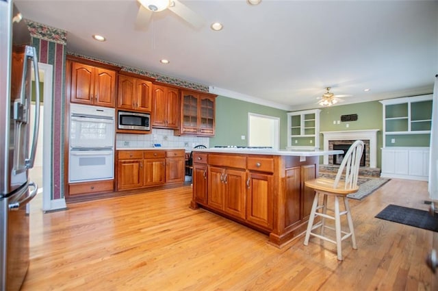 kitchen featuring stainless steel appliances, light countertops, a ceiling fan, a kitchen island, and a kitchen bar