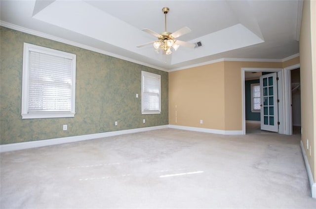 unfurnished room featuring a tray ceiling, carpet flooring, a ceiling fan, and baseboards