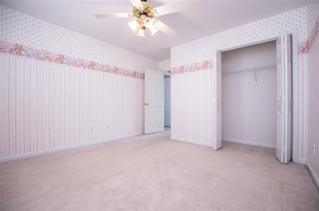 unfurnished bedroom with a closet, light carpet, ceiling fan, baseboards, and wallpapered walls