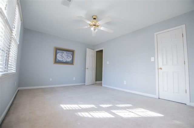 unfurnished room with baseboards, a ceiling fan, and light colored carpet