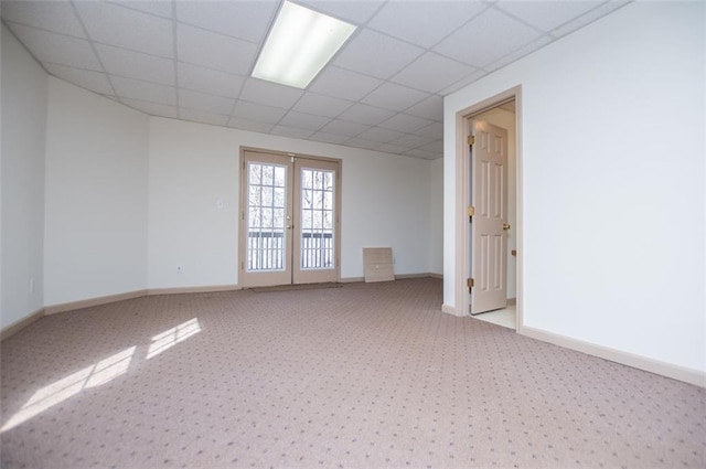 unfurnished room with french doors, light colored carpet, a paneled ceiling, and baseboards