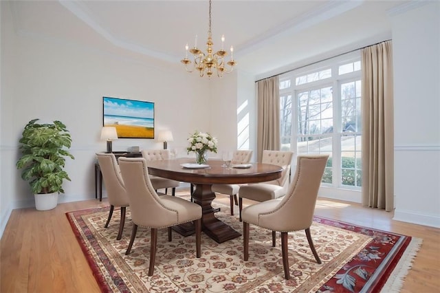 dining room featuring a tray ceiling, a notable chandelier, light wood finished floors, ornamental molding, and baseboards