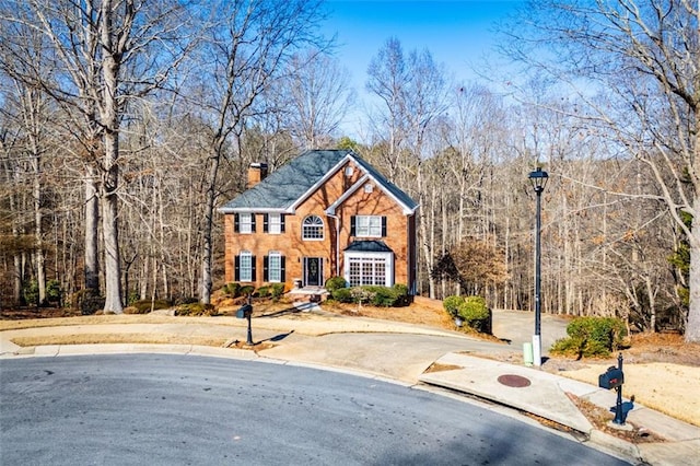 view of front of property featuring a chimney and a view of trees