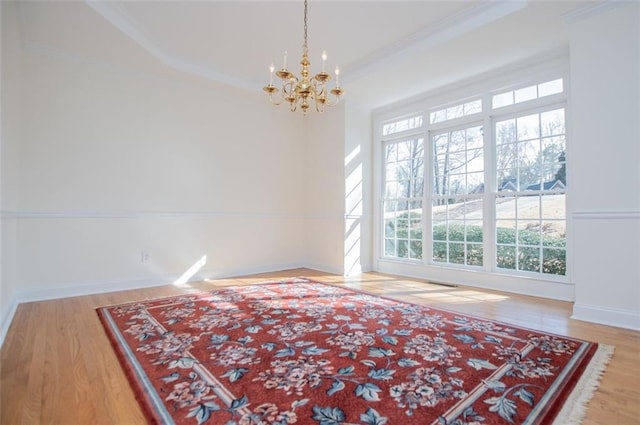 unfurnished room featuring baseboards, a chandelier, wood finished floors, and crown molding