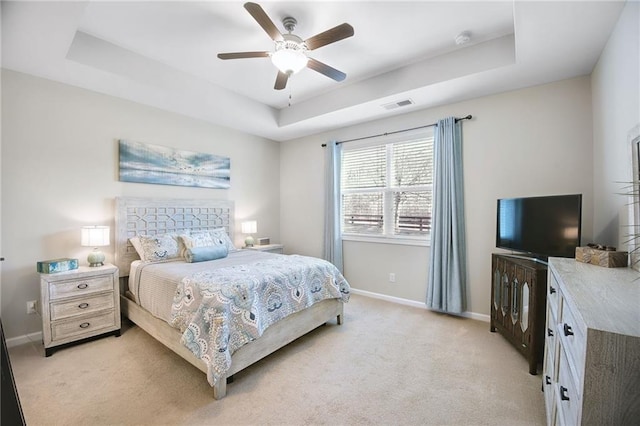 bedroom with light carpet, ceiling fan, and a raised ceiling