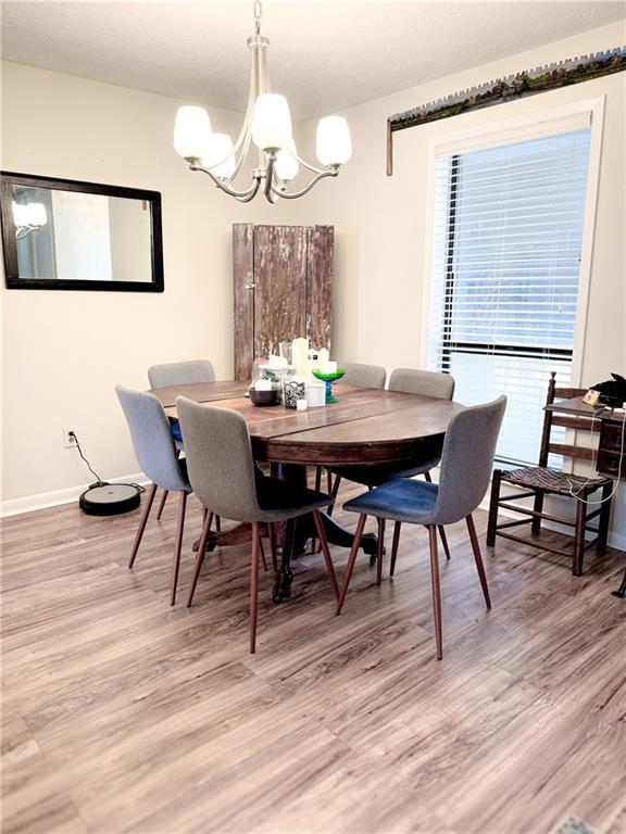 dining space featuring baseboards, light wood-style floors, and a chandelier