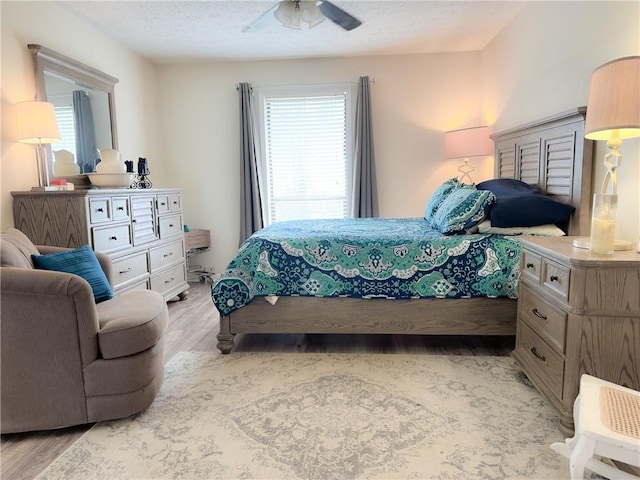 bedroom featuring multiple windows, light wood finished floors, and a textured ceiling