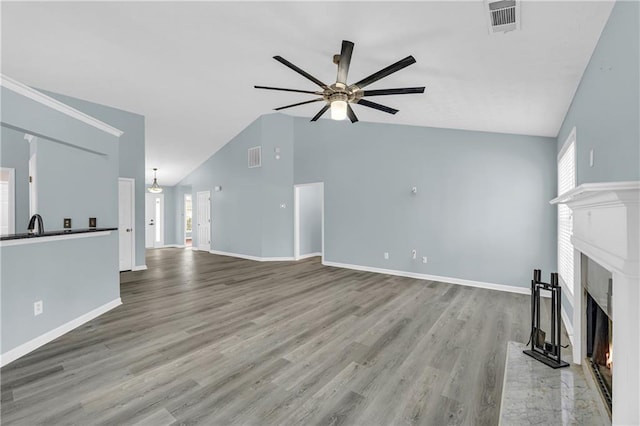 unfurnished living room featuring high vaulted ceiling, a high end fireplace, light hardwood / wood-style floors, and ceiling fan