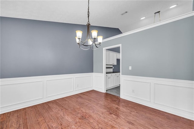 unfurnished dining area with a notable chandelier and hardwood / wood-style floors