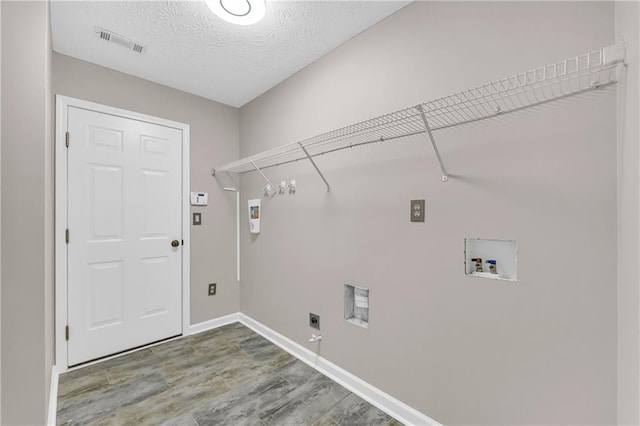 clothes washing area with hookup for a washing machine, hookup for an electric dryer, and a textured ceiling