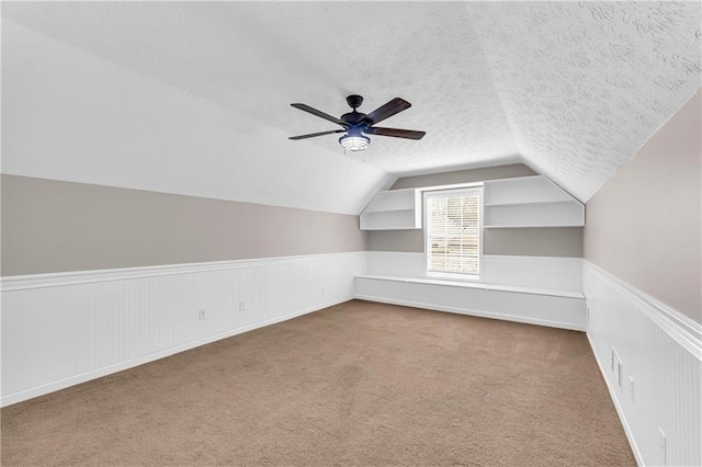 additional living space featuring vaulted ceiling, carpet flooring, ceiling fan, and a textured ceiling