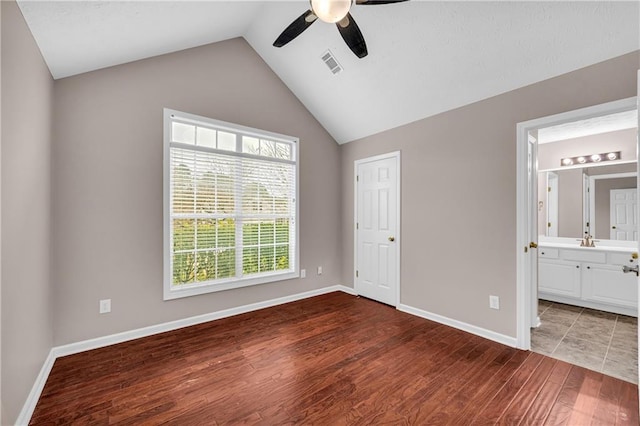 unfurnished bedroom featuring ensuite bathroom, hardwood / wood-style floors, lofted ceiling, sink, and ceiling fan