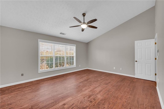 empty room with vaulted ceiling, hardwood / wood-style floors, a textured ceiling, and ceiling fan