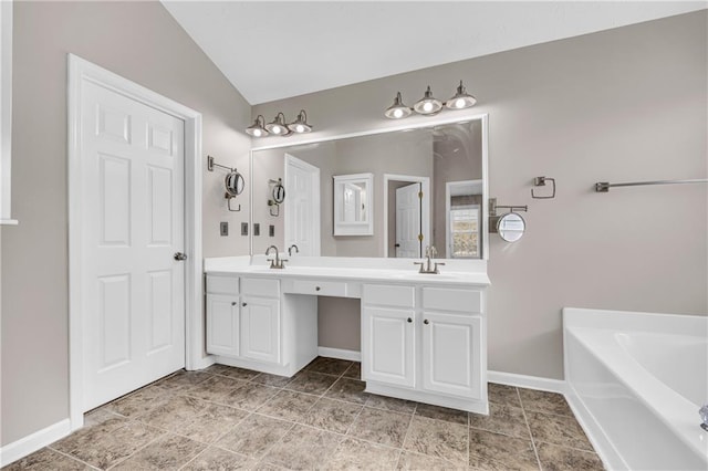 bathroom with lofted ceiling, a tub to relax in, and vanity