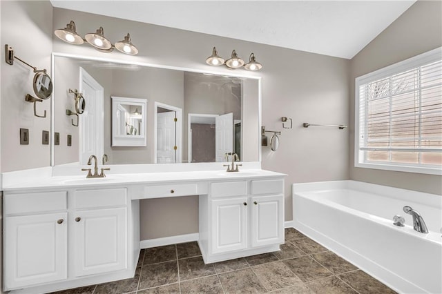 bathroom with lofted ceiling, vanity, and a tub