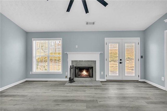 unfurnished living room featuring light hardwood / wood-style flooring, a wealth of natural light, french doors, and ceiling fan