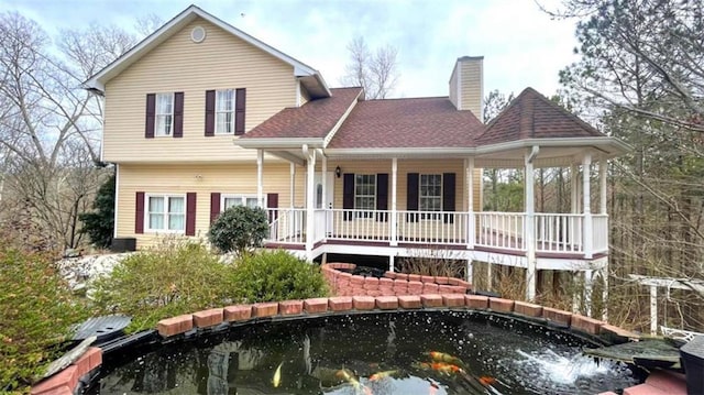 view of front of property featuring covered porch, a chimney, and roof with shingles