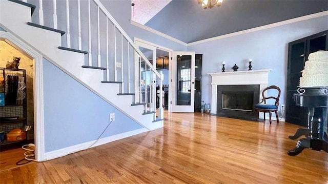 living room with a fireplace with flush hearth, ornamental molding, wood finished floors, stairway, and baseboards