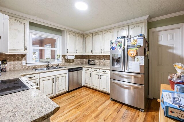 kitchen with appliances with stainless steel finishes, sink, ornamental molding, light hardwood / wood-style floors, and decorative backsplash