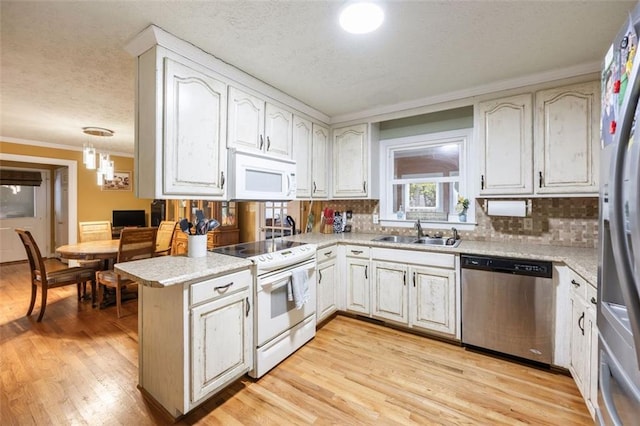 kitchen with light hardwood / wood-style flooring, kitchen peninsula, stainless steel appliances, sink, and white cabinetry