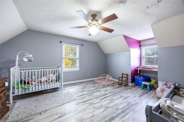 bedroom with vaulted ceiling, wood-type flooring, a textured ceiling, and a nursery area