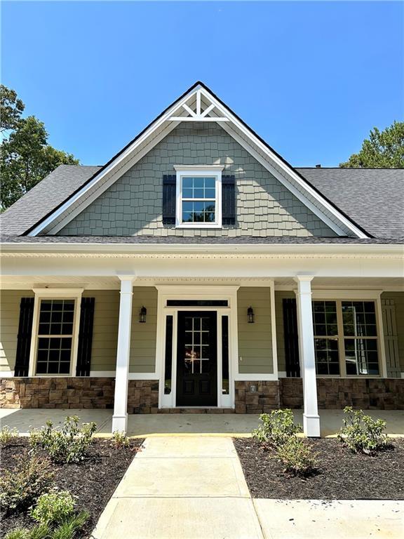 view of front facade featuring stone siding and a shingled roof