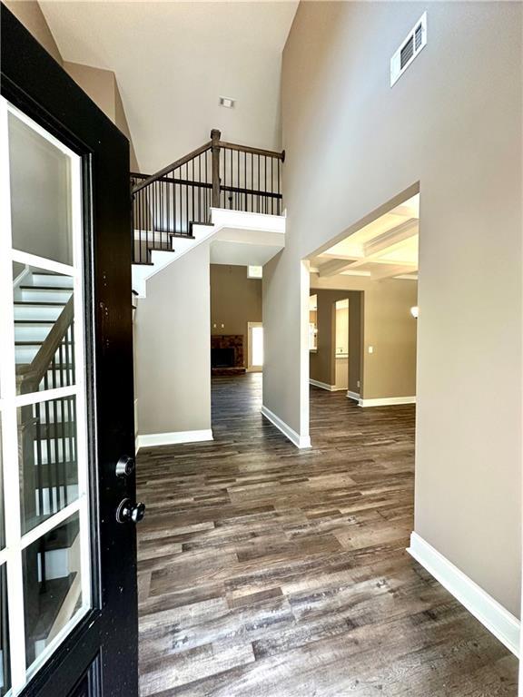 foyer with a high ceiling, visible vents, baseboards, stairs, and dark wood-style floors