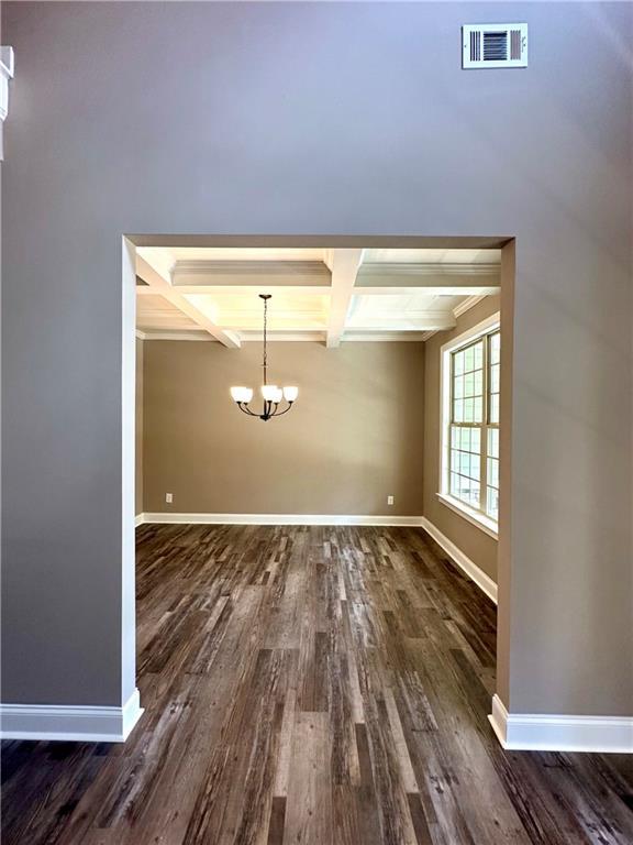 unfurnished dining area featuring a notable chandelier, coffered ceiling, visible vents, and baseboards