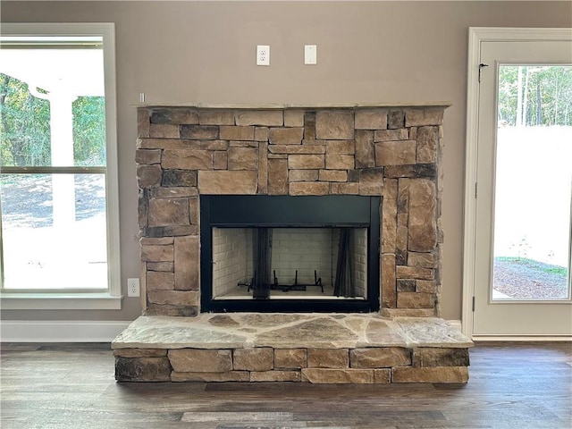 room details with a stone fireplace, wood finished floors, and baseboards