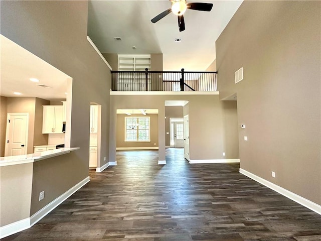 unfurnished living room with ceiling fan, dark wood-type flooring, visible vents, and baseboards