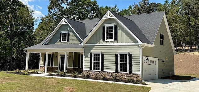 view of front of home with a garage, stone siding, a porch, board and batten siding, and a front yard