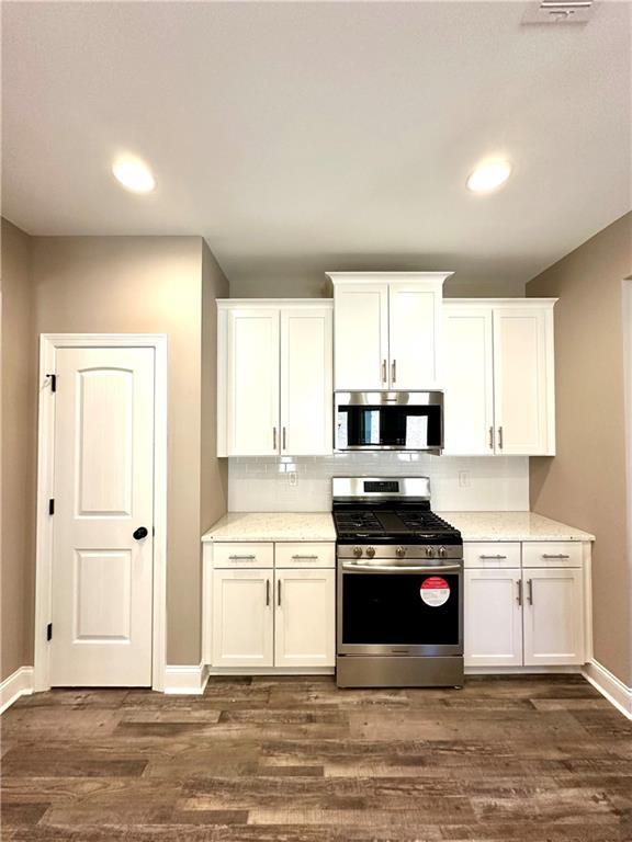 kitchen featuring light countertops, appliances with stainless steel finishes, dark wood-type flooring, and white cabinets