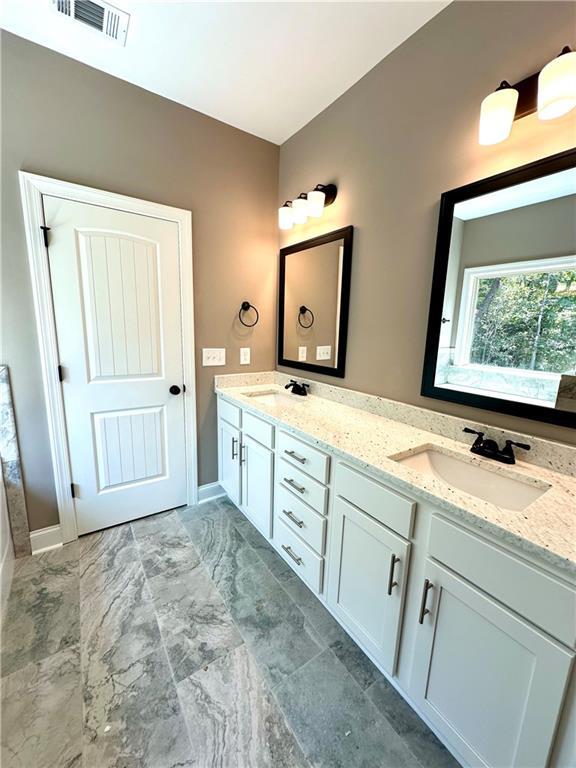 full bath with double vanity, marble finish floor, visible vents, and a sink