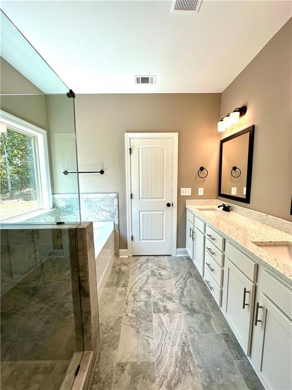 full bathroom with double vanity, baseboards, visible vents, a garden tub, and a sink