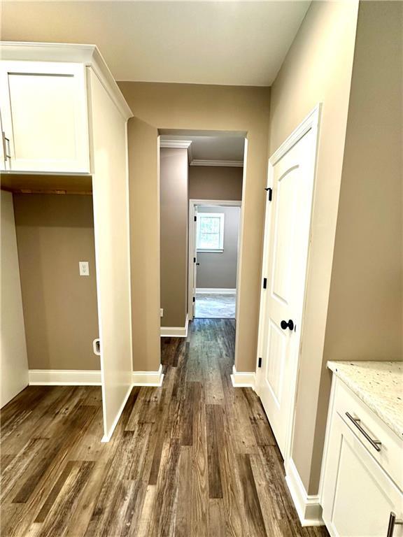 corridor with crown molding, dark wood finished floors, and baseboards