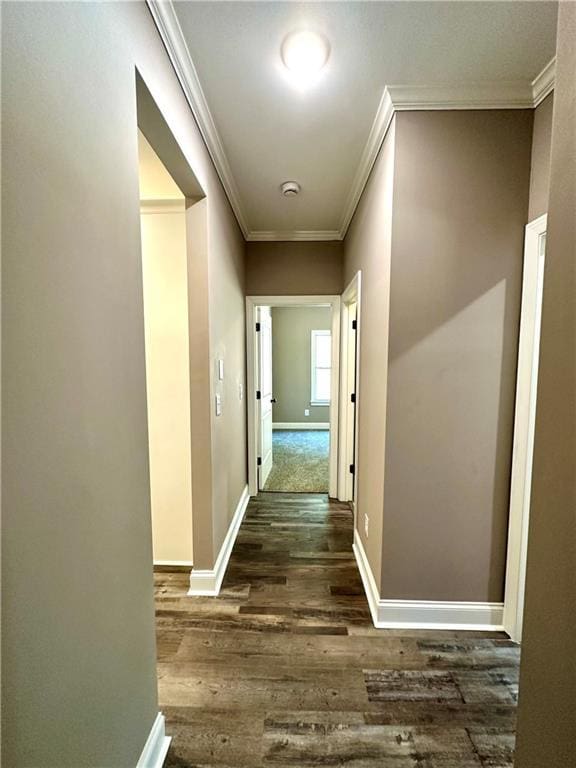 corridor with ornamental molding, dark wood-style flooring, and baseboards