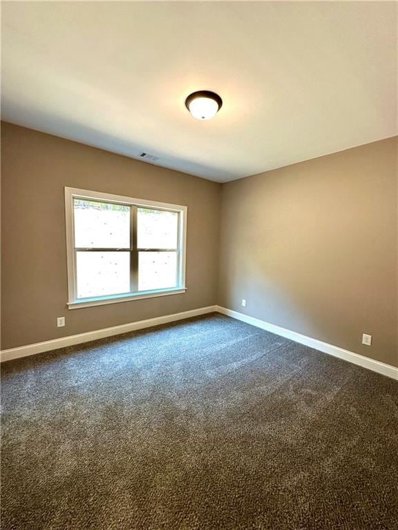 unfurnished room with carpet, visible vents, and baseboards