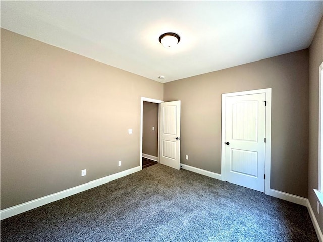 unfurnished bedroom featuring baseboards and dark carpet